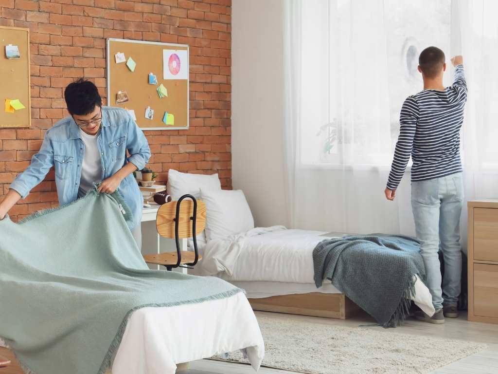 two college boys cleaning their dorm room together 