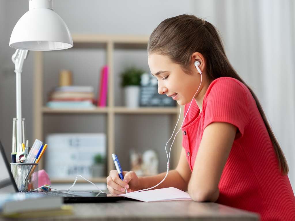 female student studying at her desk with earphones on