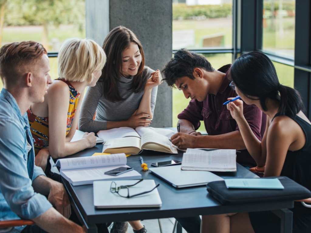 group of multi-cultural students reading books on a table