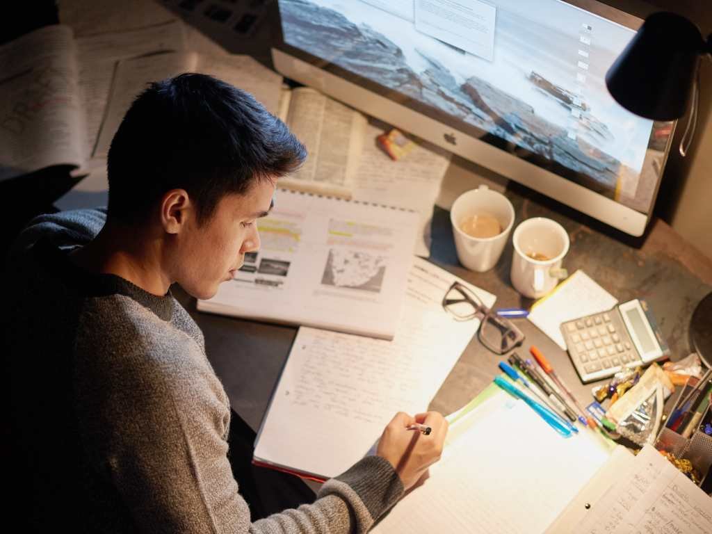 young asian man cramming while studying on his study desk