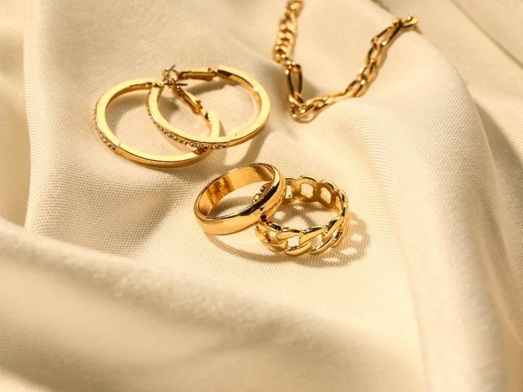Two rings, a pair of earrings and a necklace on a white fabric