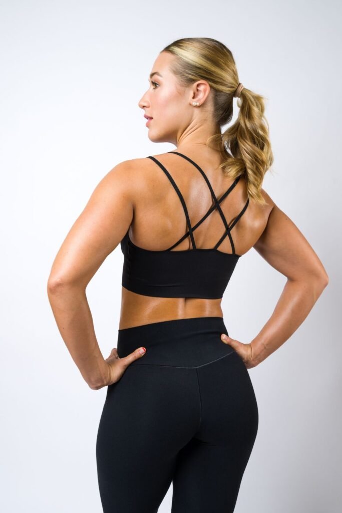 young blonde woman with her back turned to the camera wearing a black sports bra and black leggings