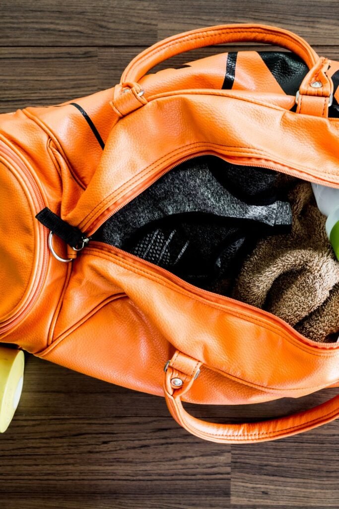 open orange gym bag with gym clothes and a towel inside