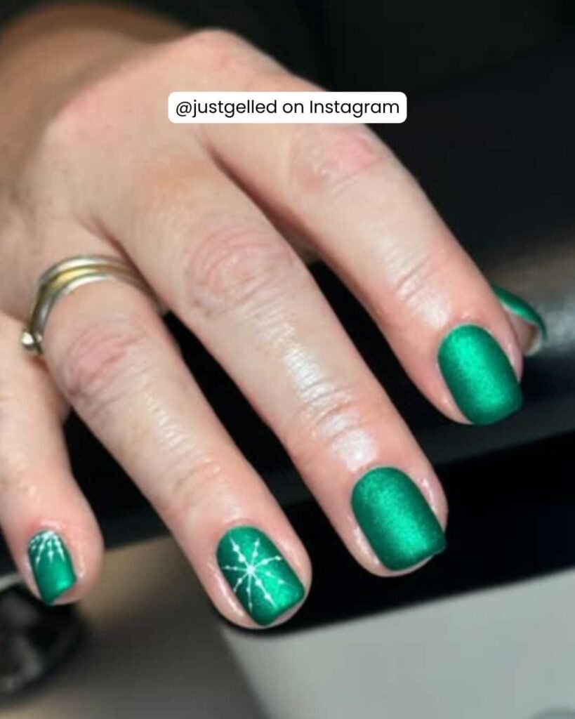 Sophisticated matte emerald green nails with sparkling starburst accents, inspired by "Wicked."
