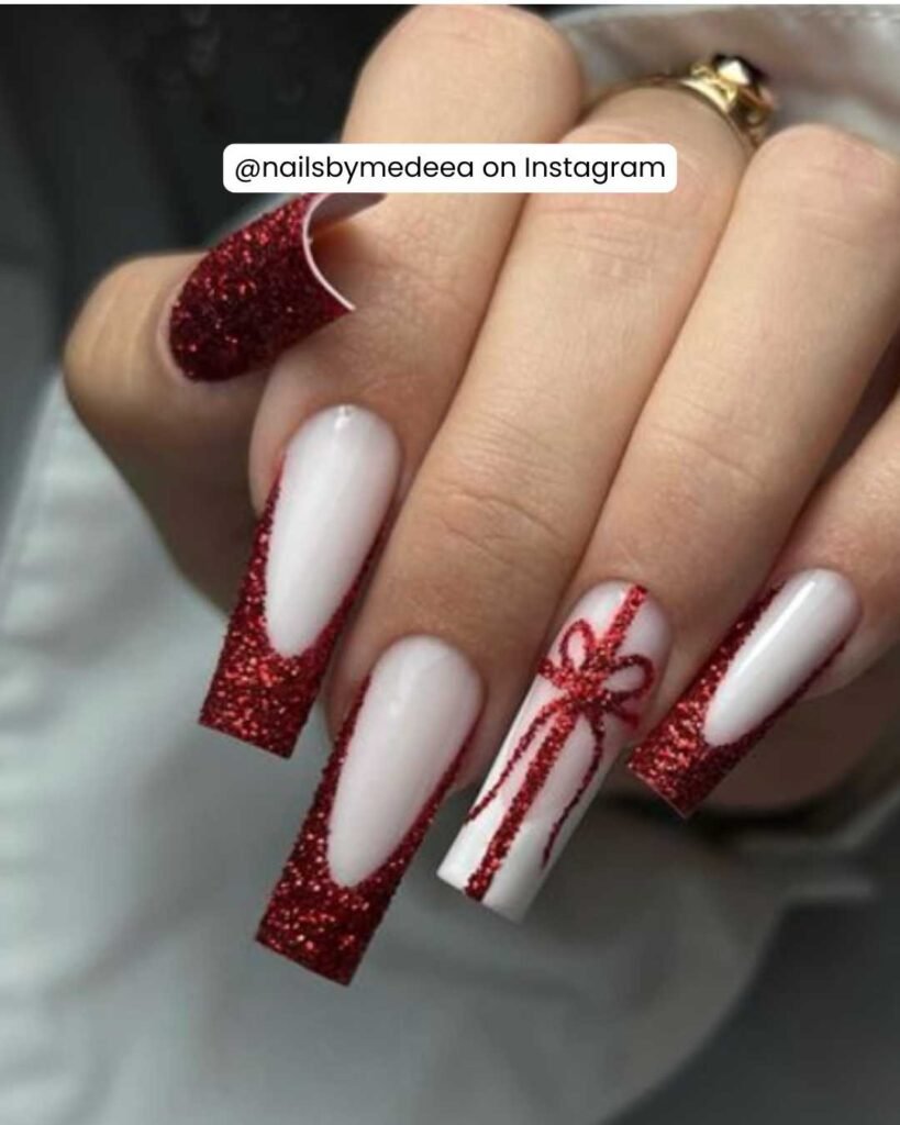 Red glitter coffin nails with a crisp white base and a festive gift bow design.