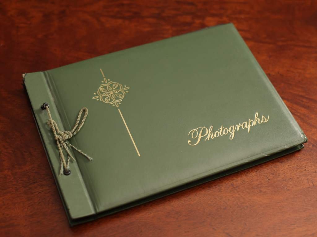 A green photo album on the table with the word 'photographs' embossed.