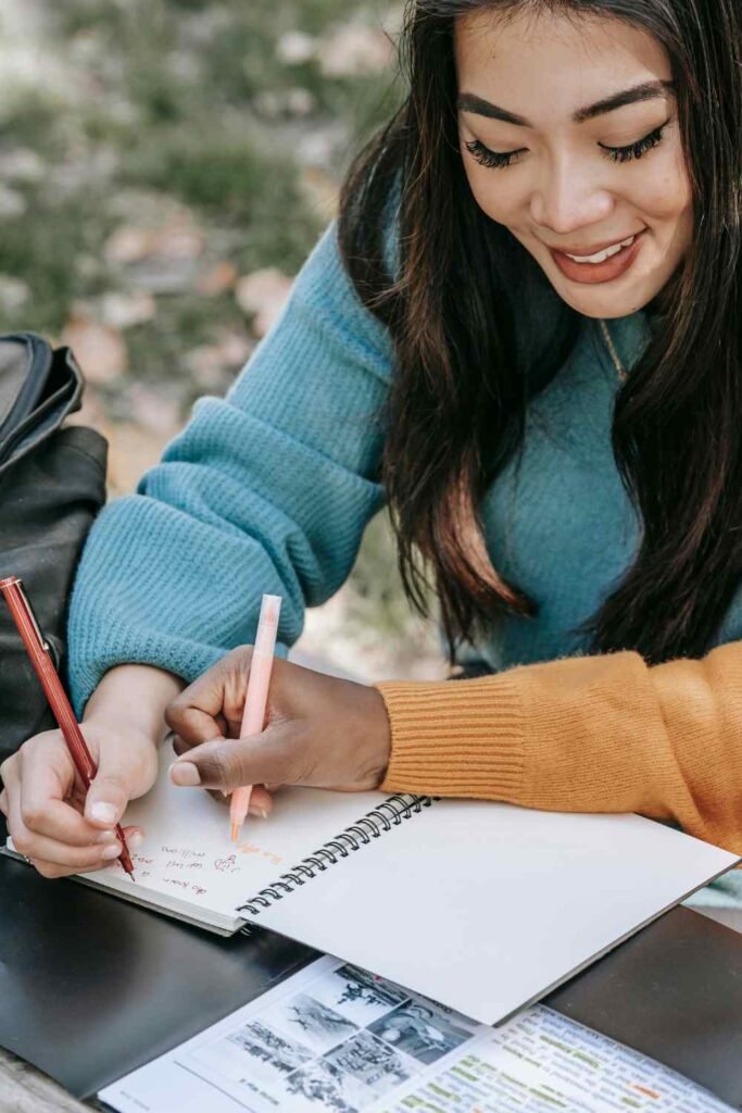 asian woman studying on a table with her notebook open and she is writing something down