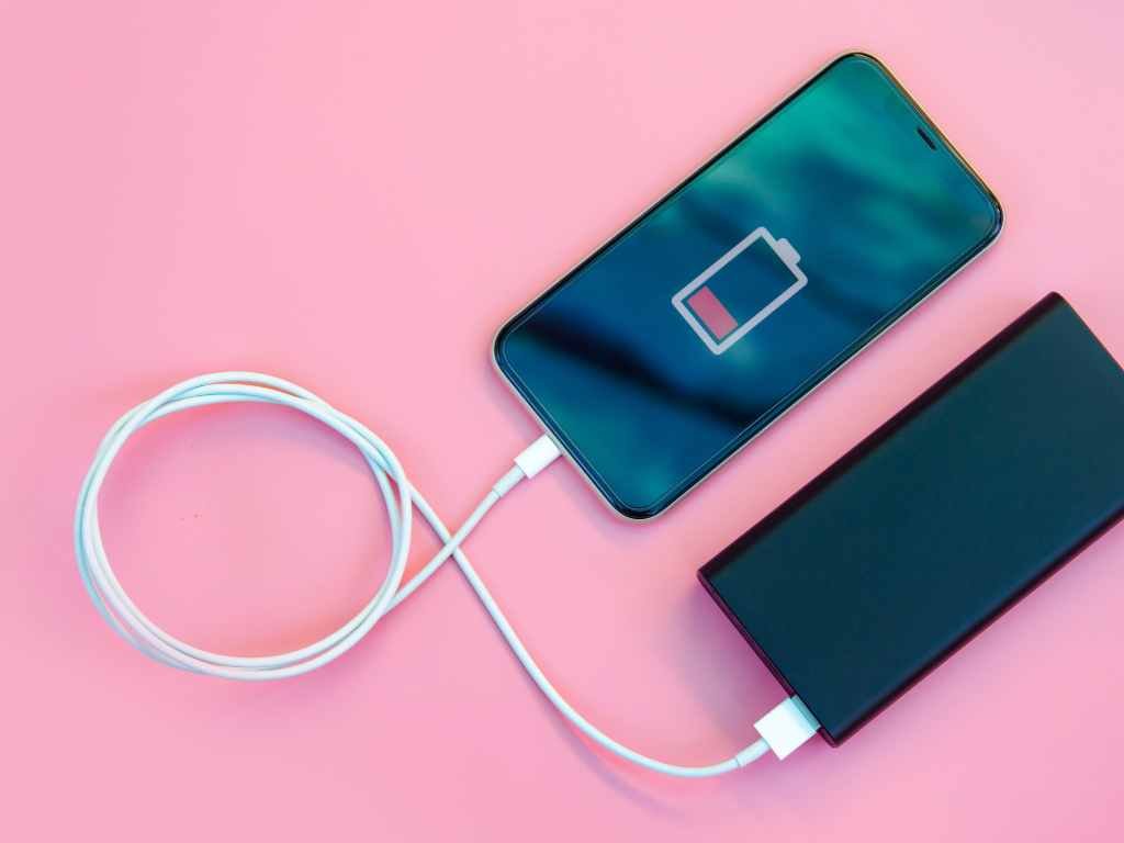 portable power bank with a phone that has low battery on a pink table