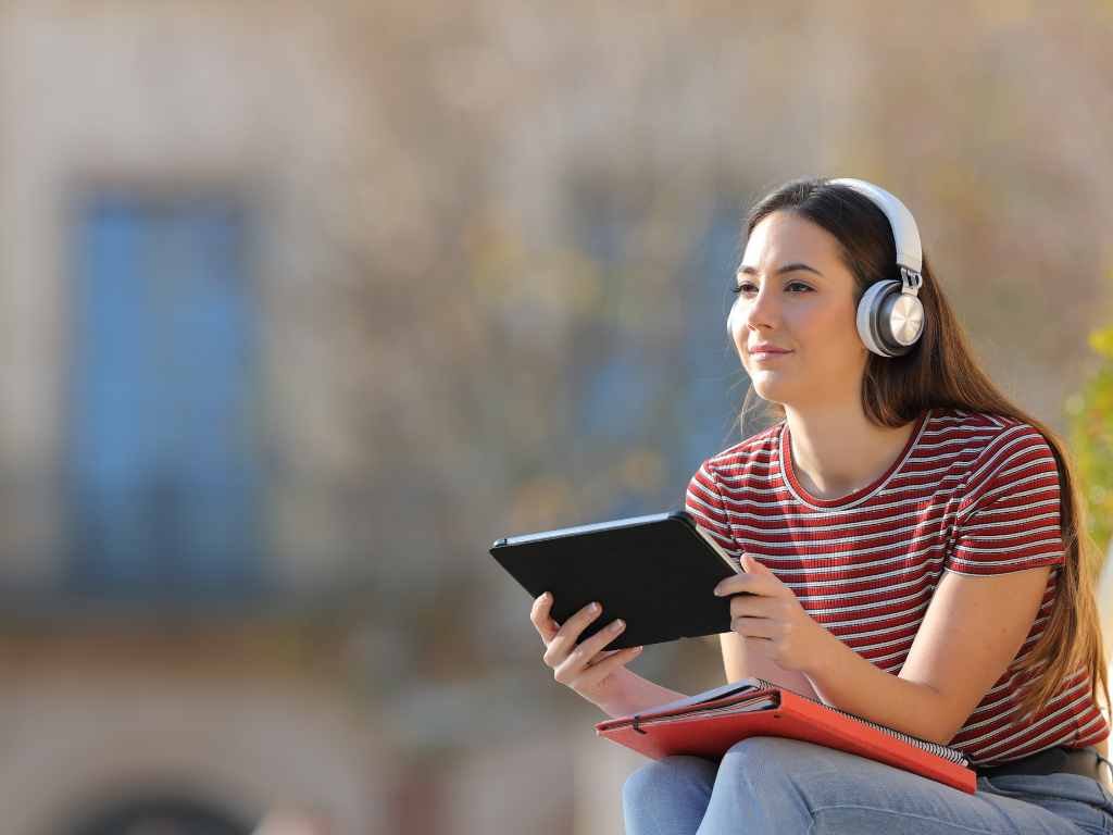 young woman listening to her ipad with headphones on