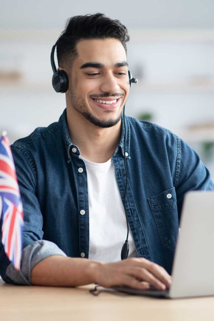 young handsome middle eastern man with a headset smiling at his laptop