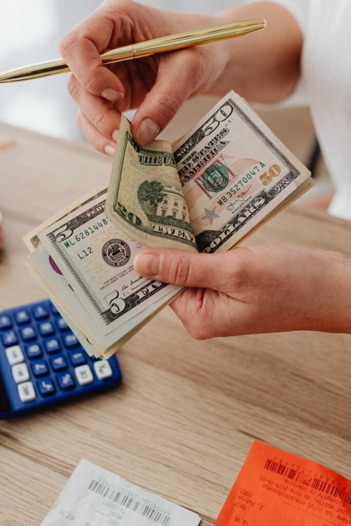 person counting dollars on top of a table with a calculator on it