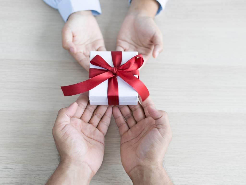 person giving a white box with a red ribbon