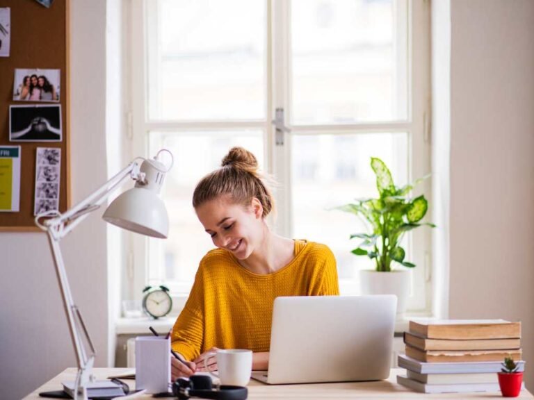 blonde student at her desk smiling while she studies