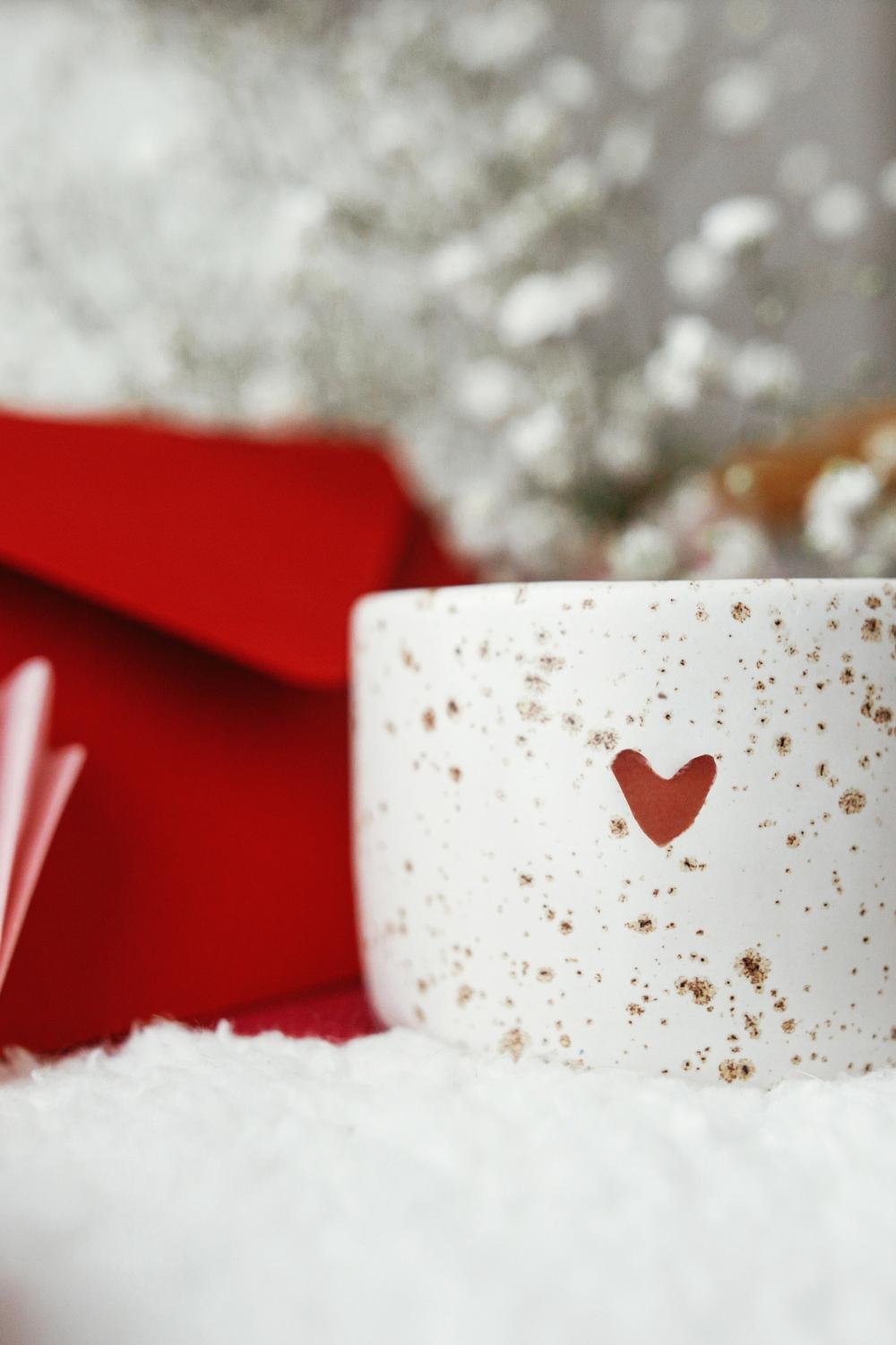 A white ceramic mug adorned with gold speckled dots and a heart shape at the center.