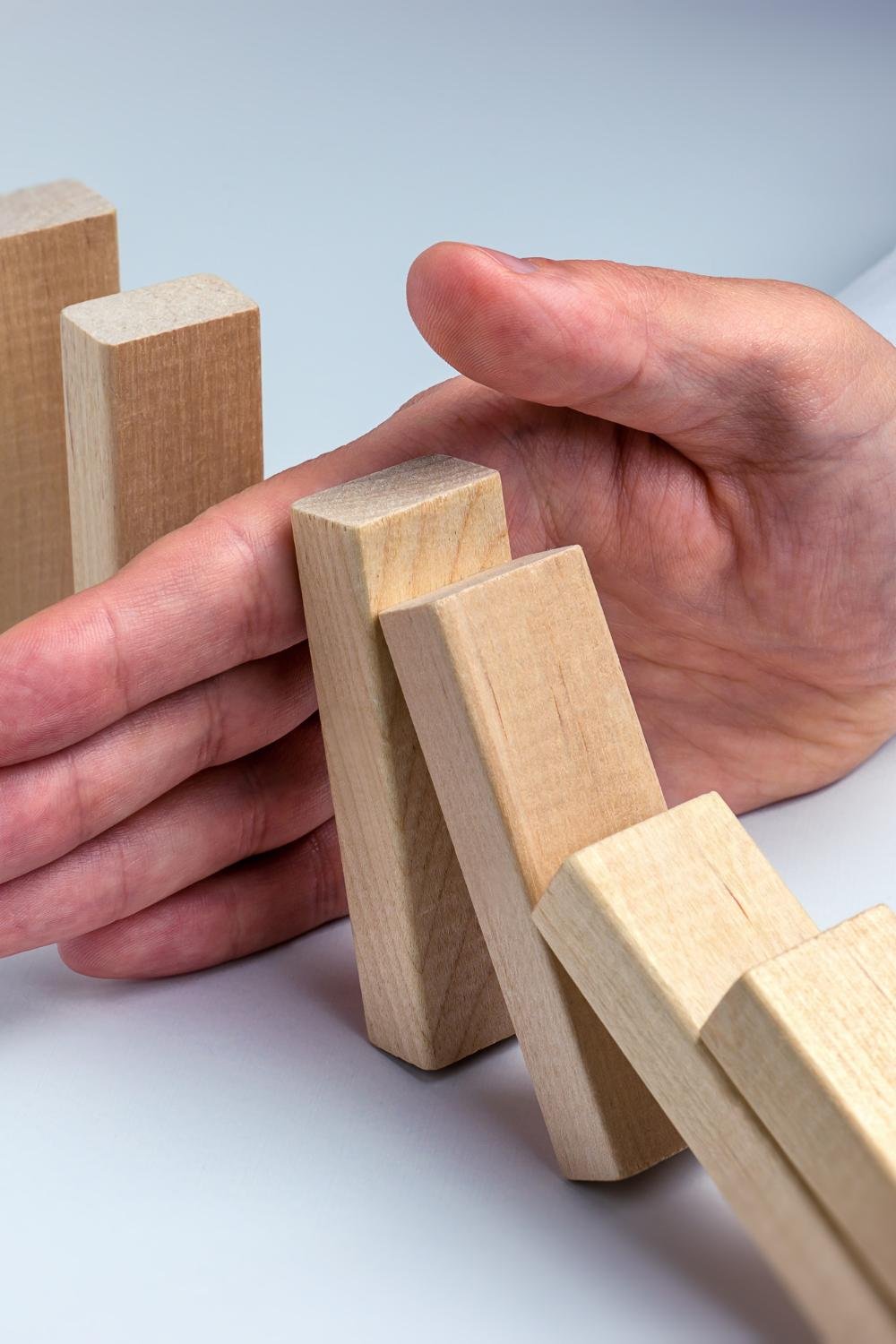 A hand reaching out, appearing to push down a line of dominoes.