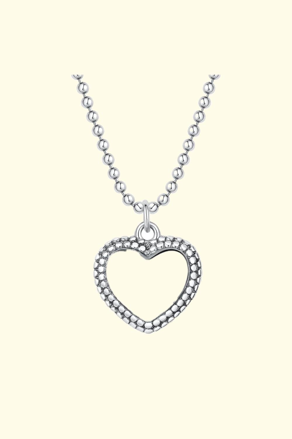 A silver necklace with a heart-shaped pendant.