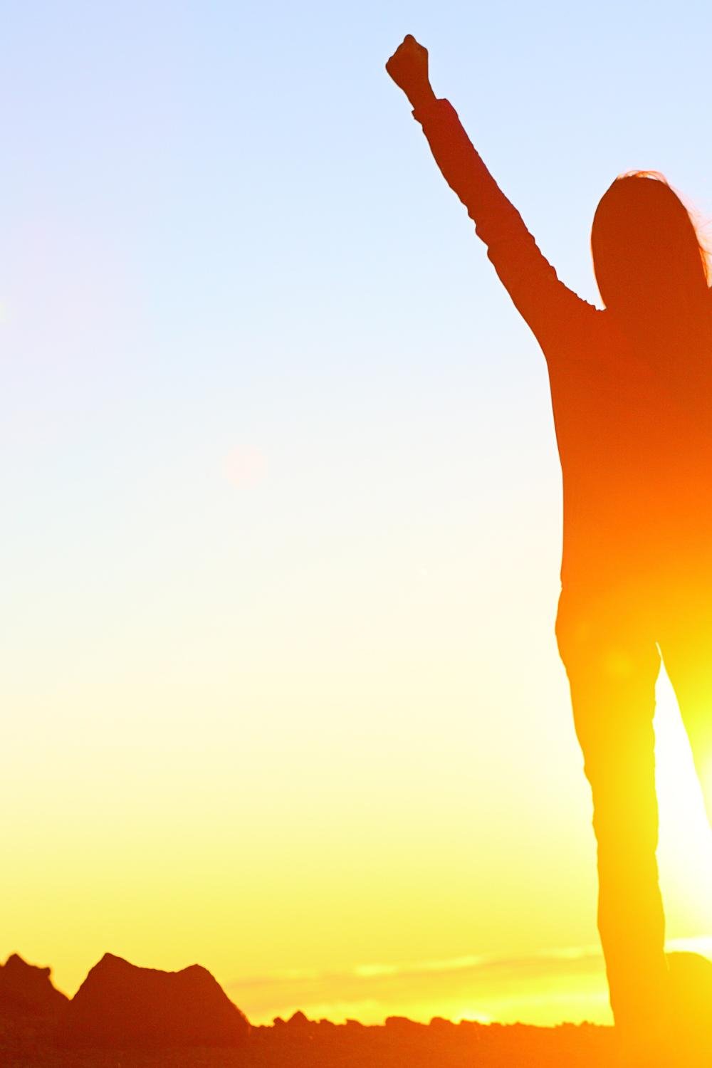 A woman with her back to the camera, raising her fists triumphantly in the air.