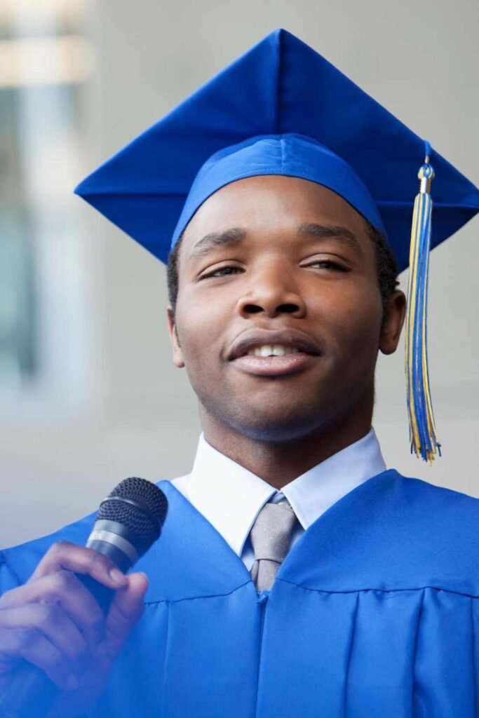 young black man in a navy blue toga and graduation hat giving a speech