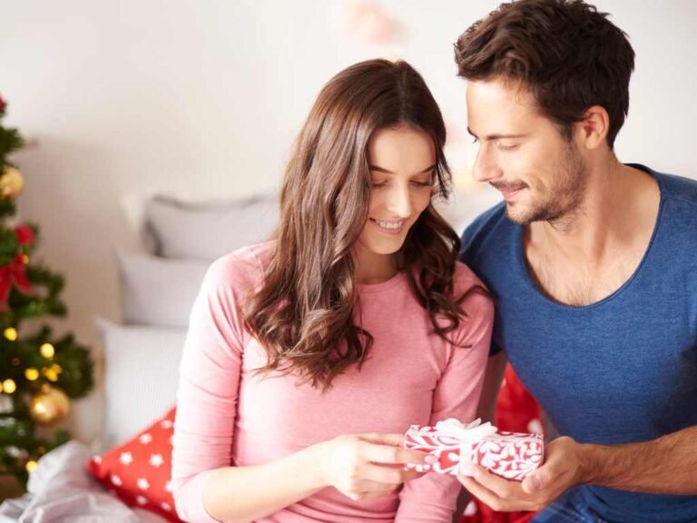 young woman giving her boyfriend a gift wrapped in a bow