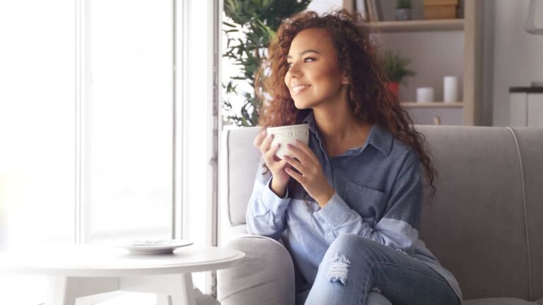 young black american woman drinking tea while looking out the window